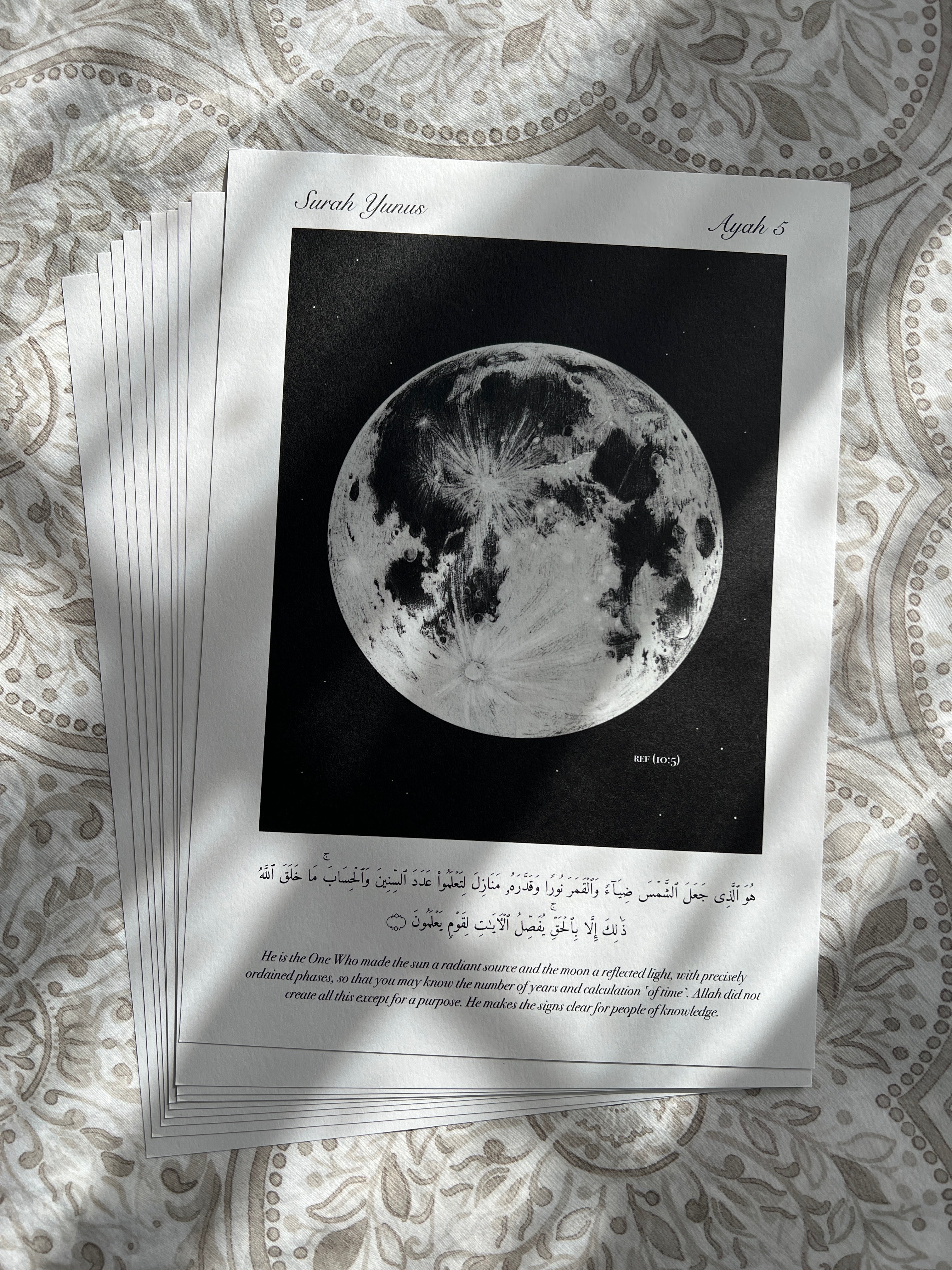Stack of minimalistic islamic prints depicting the verse (10:5) with a monochrome full moon on a black background. Below is the verse it is inspired by. The perfect reminder and decor for any muslim.